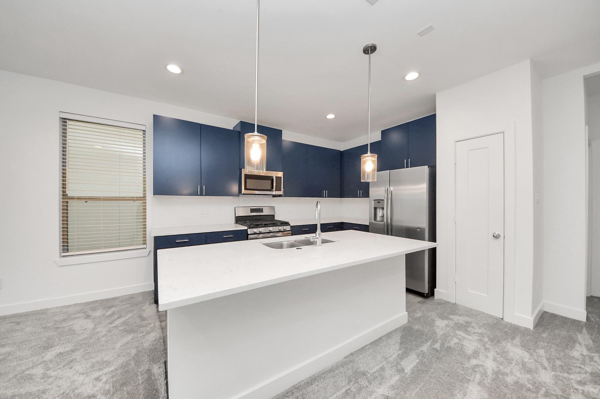18527 Centro Row Conroe, TX 77385 - Photo 11 of 44 Deep navy cabinetry provides a bold, sophisticated contrast to the pristine marble-style island and chic pendant illumination—the ultimate stage for the home chef.