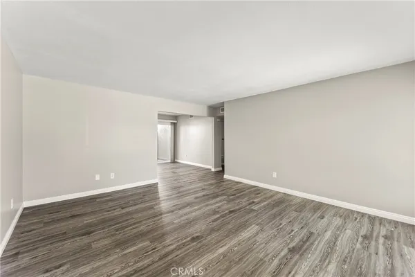 a view of an empty room with wooden floor and closet