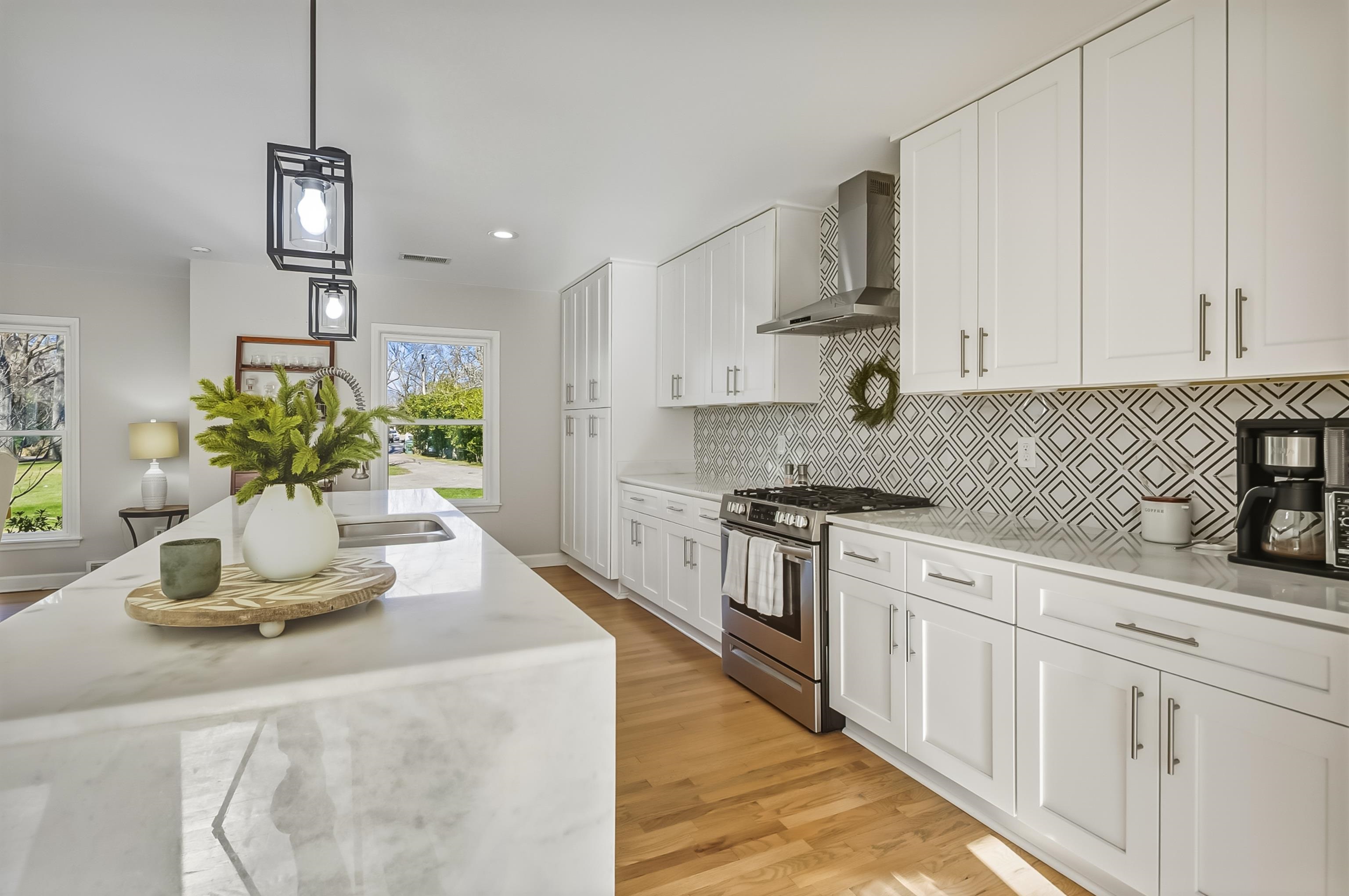 5155 Shady Grove Road Memphis, TN 38117 - Photo 13 of 40 Kitchen featuring decorative light fixtures, gas stove, light stone countertops, wall chimney exhaust hood, and white cabinetry