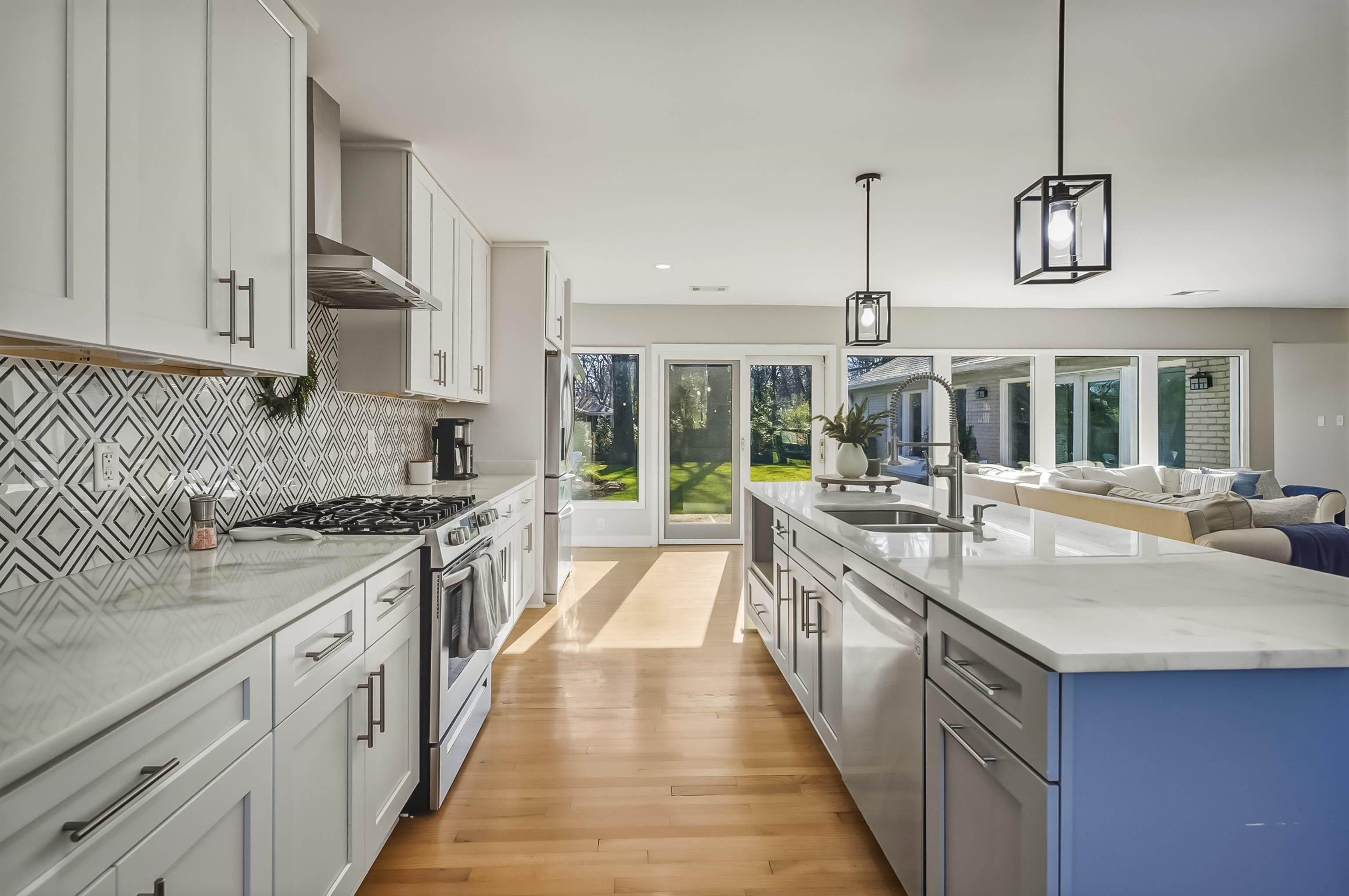 5155 Shady Grove Road Memphis, TN 38117 - Photo 14 of 40 Kitchen with stainless steel appliances, light stone countertops, white cabinets, wall chimney range hood, and hanging light fixtures