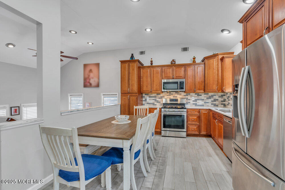 6 Coral Drive Hazlet, NJ 07730 - Photo 7 of 23 a kitchen with stainless steel appliances a stove a sink dishwasher a refrigerator and a dining table with wooden floor