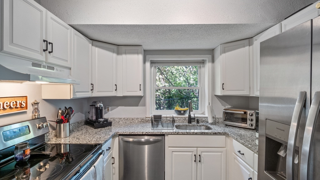 4 Duck Pond Road, Unit 218 Beverly, MA 01915 - Photo 7 of 19 a kitchen with granite countertop stainless steel appliances a sink window and cabinets