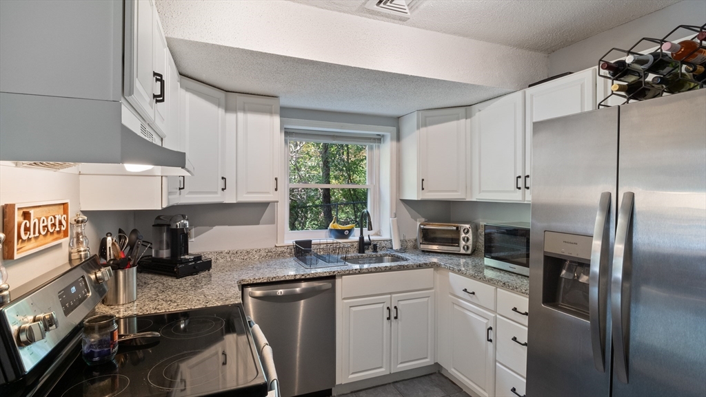 4 Duck Pond Road, Unit 218 Beverly, MA 01915 - Photo 8 of 19 a kitchen with stainless steel appliances granite countertop a sink a stove a refrigerator cabinets and a window