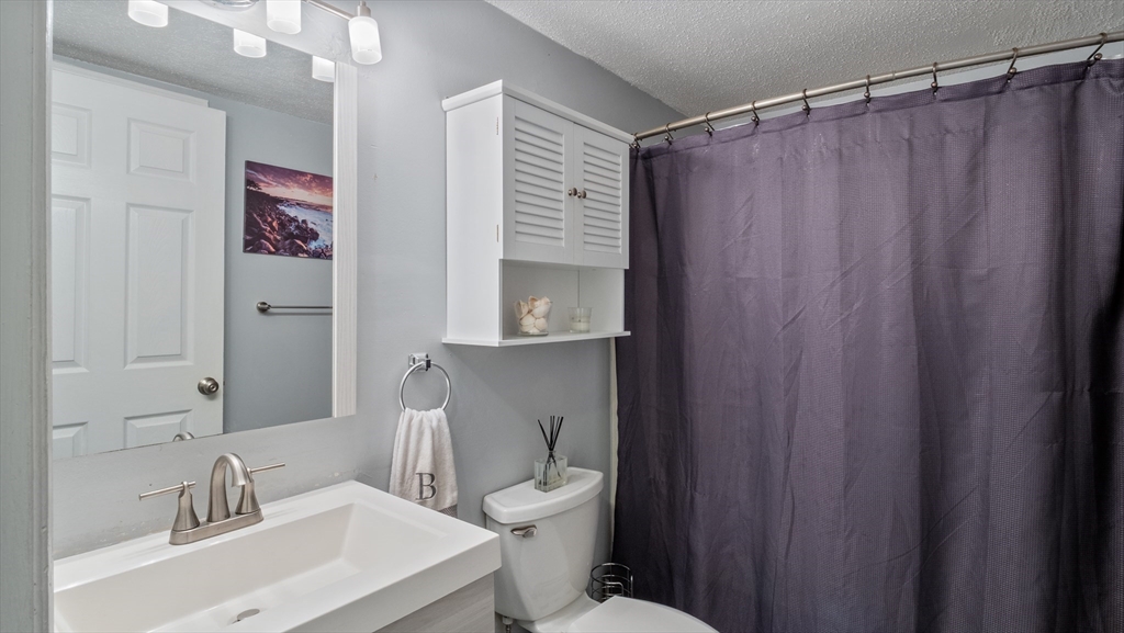 4 Duck Pond Road, Unit 218 Beverly, MA 01915 - Photo 9 of 19 a bathroom with a sink a toilet and shower curtain