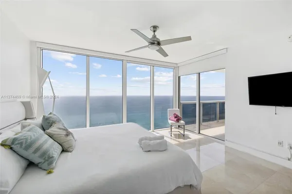 a bedroom with a large bed and a flat tv screen