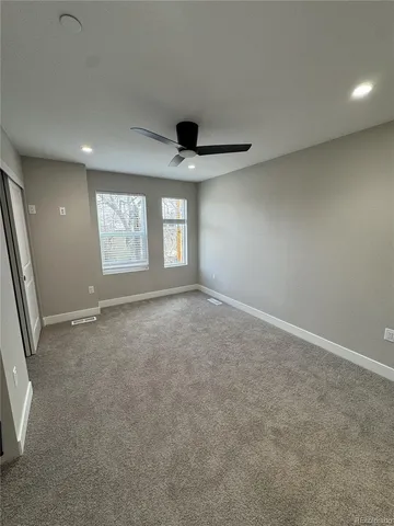 an empty room with windows and ceiling fan