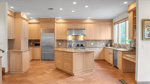 a large kitchen with stainless steel appliances granite countertop a stove a sink and a refrigerator