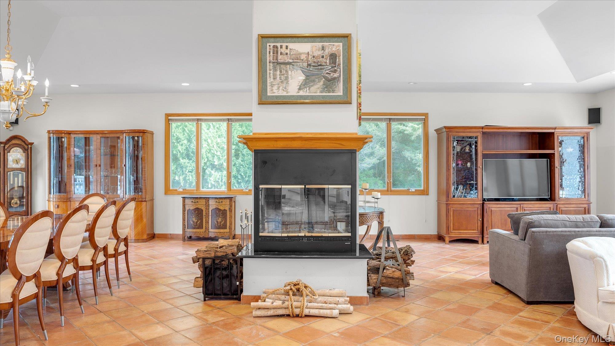 3400 Dignans Road Cutchogue, NY 11935 - Photo 8 of 34 Living room with recessed lighting, light tile patterned floors, a chandelier, and a glass covered fireplace