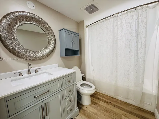 a bathroom with a granite countertop toilet sink and mirror