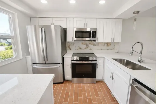 a kitchen with granite countertop a refrigerator stove and sink