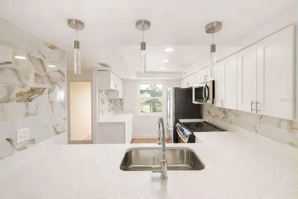 a kitchen with stainless steel appliances kitchen island granite countertop a sink and a granite counter tops