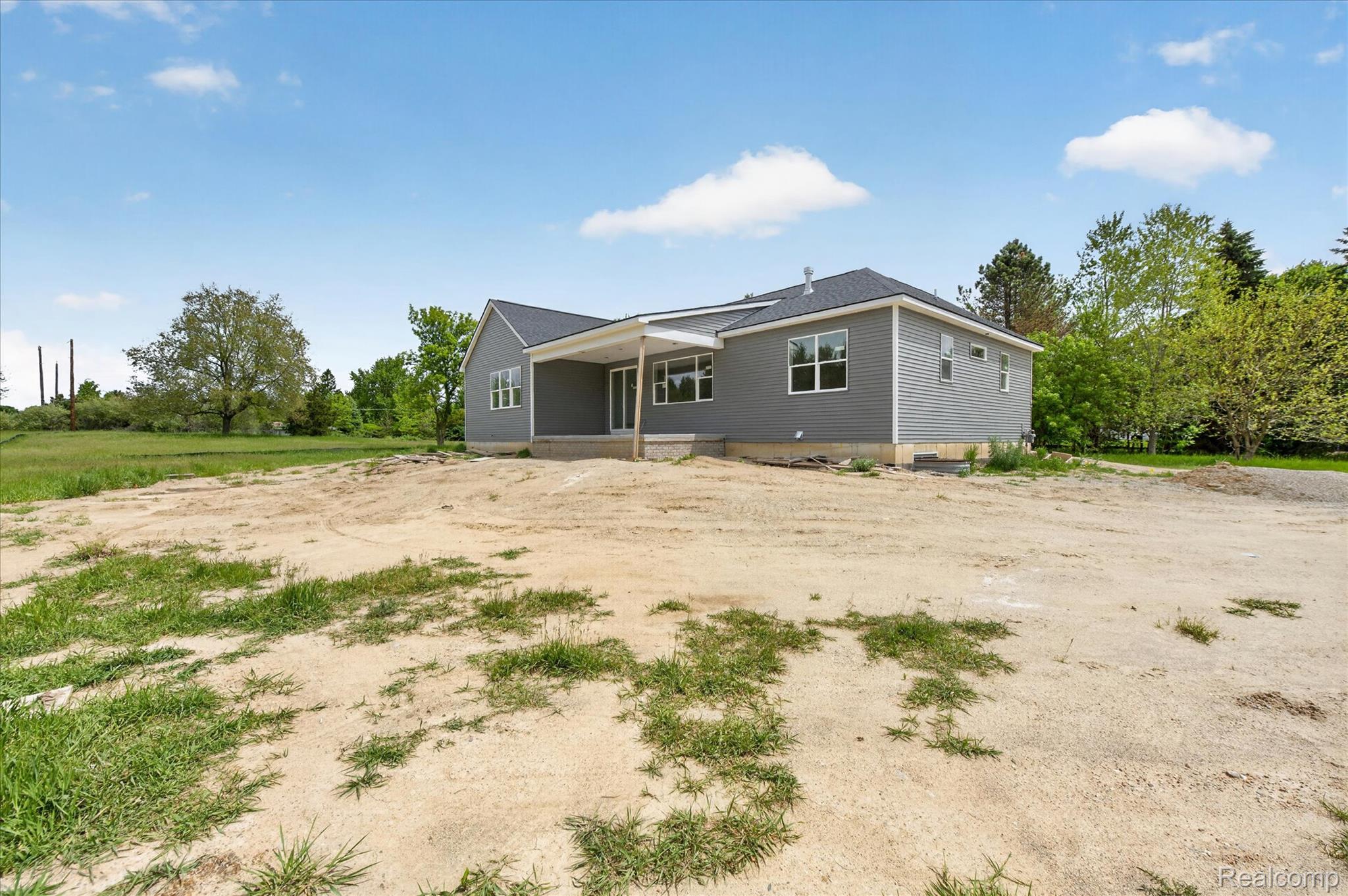 3297 Oak Grove Road Howell, MI 48855 - Photo 26 of 40 Rear view of the home with covered outdoor living space and peaceful setting.