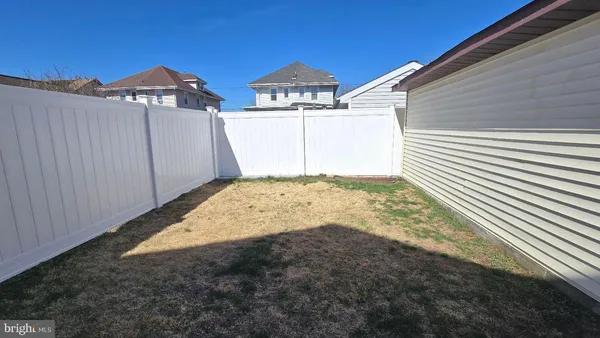 a view of a blue house with yard and a wooden fence