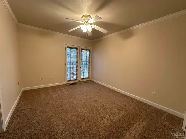 an empty room with chandelier fan and windows