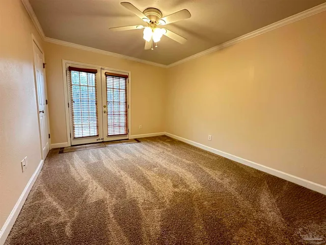 an empty room with a chandelier fan and windows
