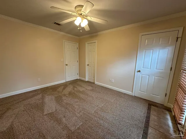 an empty room with a chandelier fan and closet area