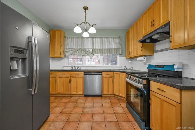 a kitchen with stainless steel appliances granite countertop a sink a stove and refrigerator