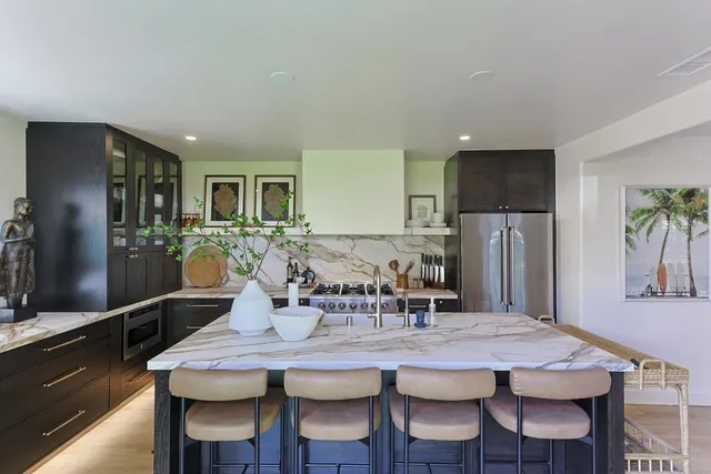 a kitchen with stainless steel appliances granite countertop a dining table chairs refrigerator and sink