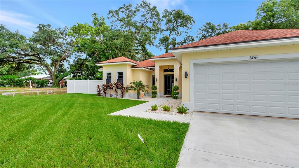 306 East Clay Avenue Brandon, FL 33510 - Photo 1 of 26 a front view of a house with a garden and trees