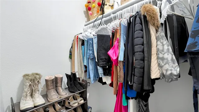 a view of walk in closet with clothes and shoes
