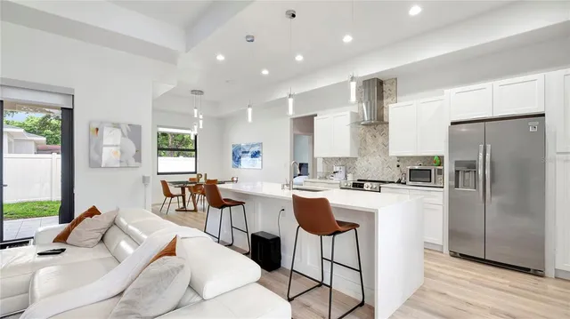 a kitchen with stainless steel appliances kitchen island granite countertop a refrigerator a stove a sink dishwasher and white cabinets with wooden floor