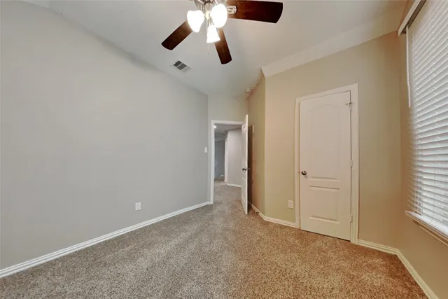 an empty room with windows and fan