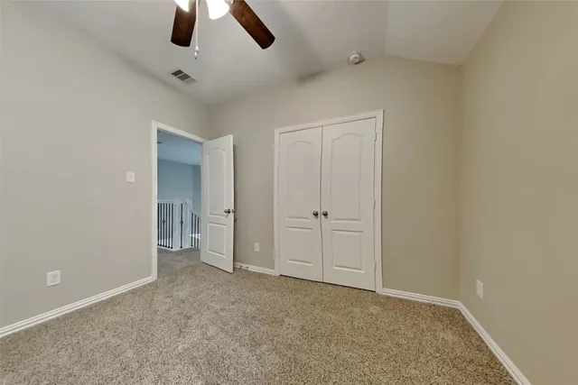 an empty room with closet and chandelier fan
