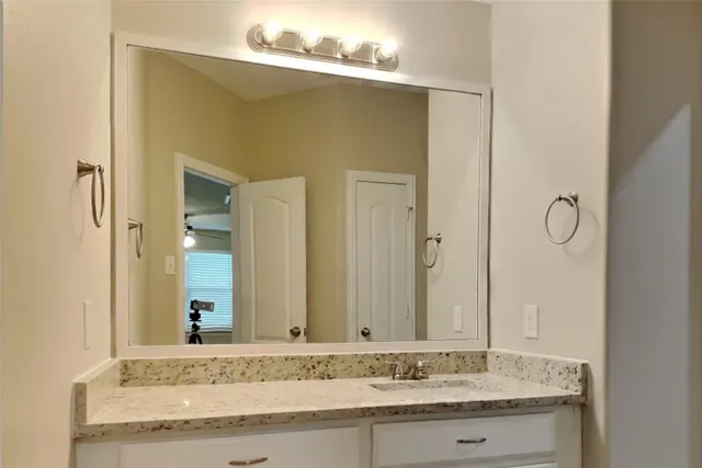 a bathroom with a granite countertop sink and a mirror