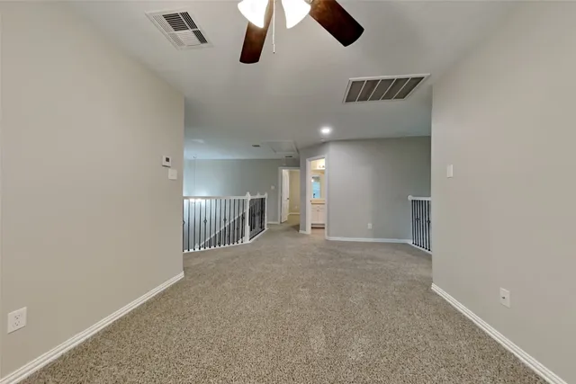 an empty room with chandelier fan and windows