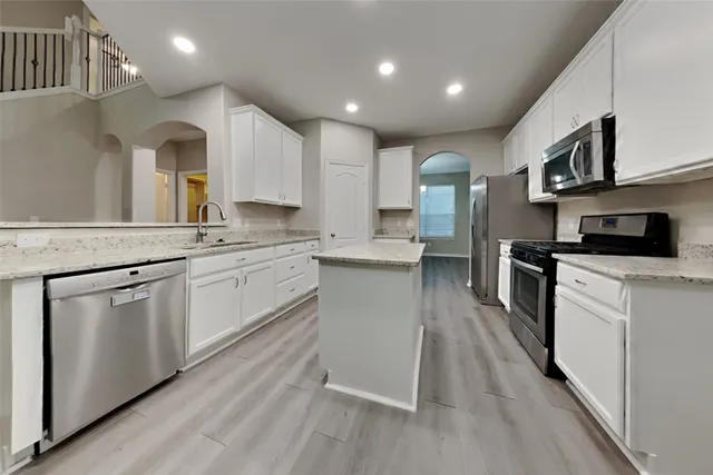 a kitchen with granite countertop a sink cabinets stainless steel appliances and a counter top space