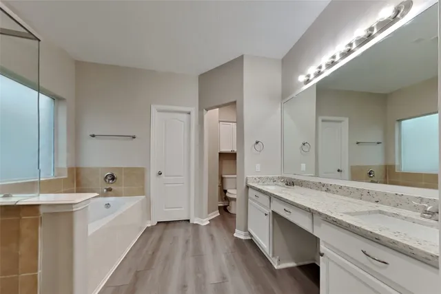 a spacious bathroom with a granite countertop double vanity sink a mirror and a bathtub