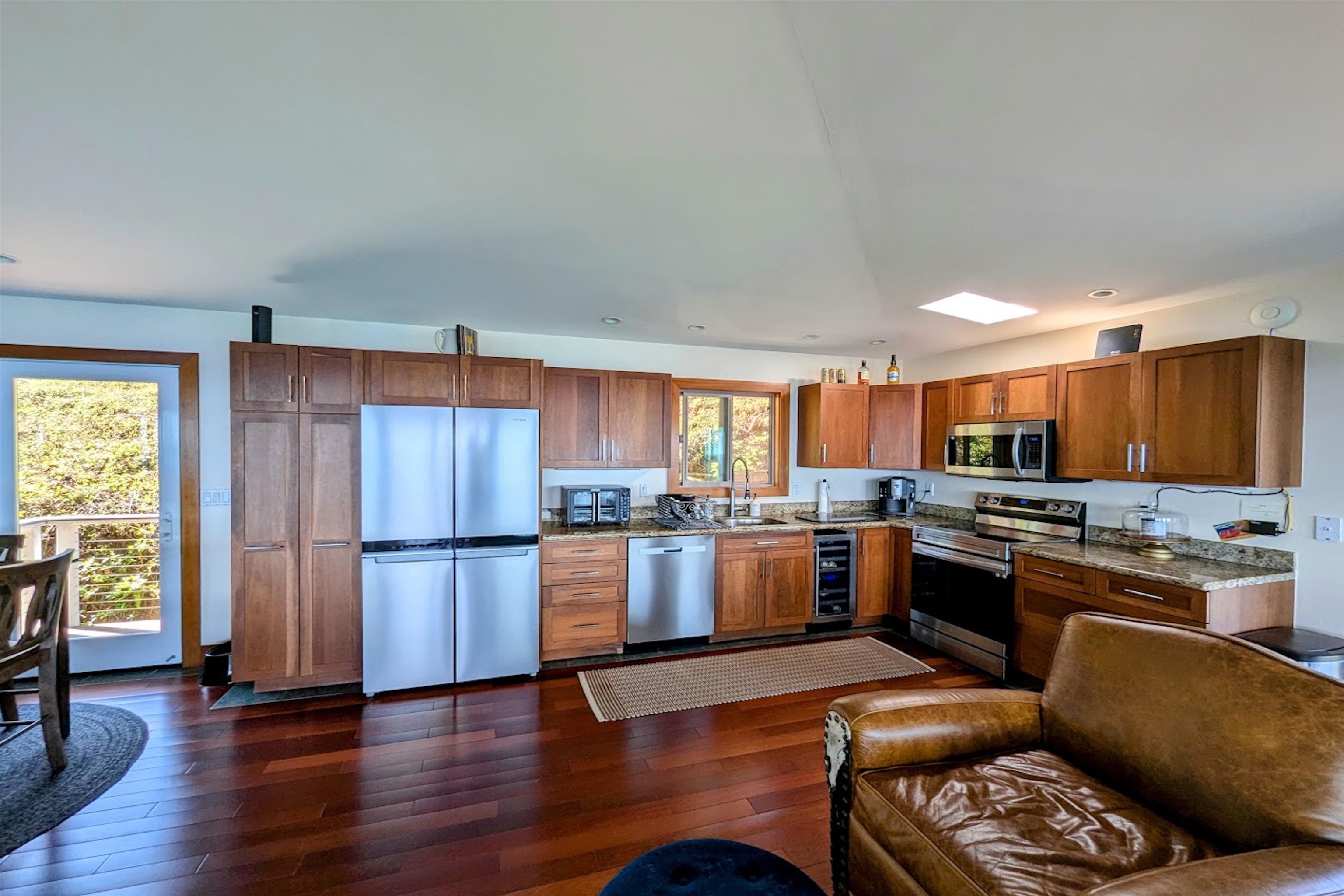 400 Mehana Road Haiku, HI 96708 - Photo 43 of 50 a kitchen with stainless steel appliances granite countertop a refrigerator a stove top oven a sink dishwasher and wooden cabinets with wooden floor