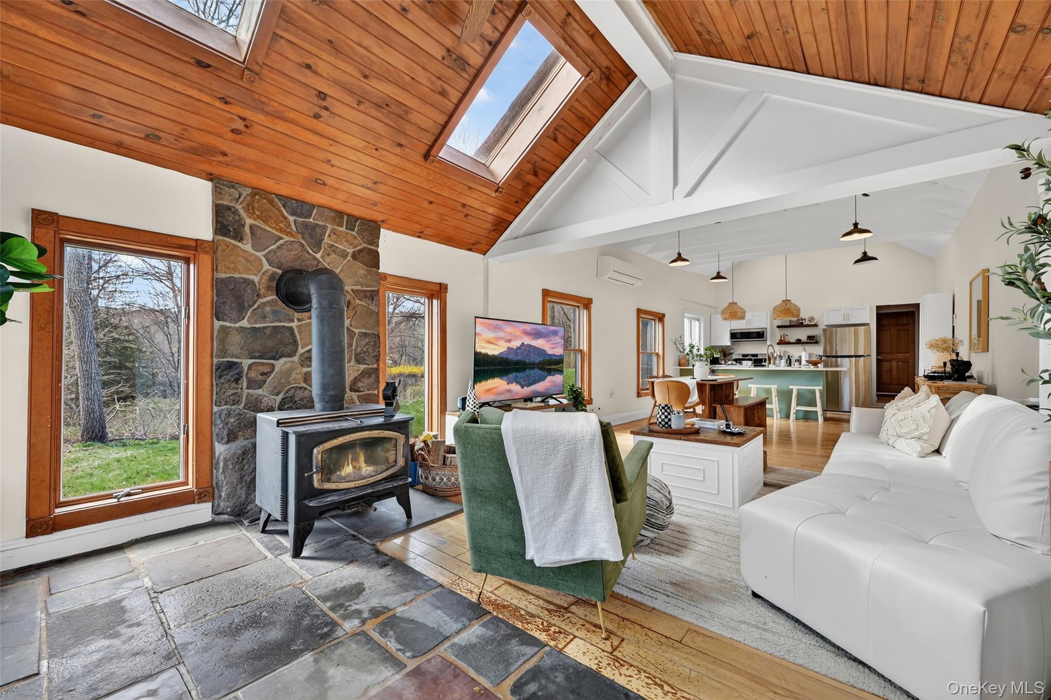 96 Lower Wisner Road Warwick, NY 10990 - Photo 14 of 34 Vaulted wood-paneled ceilings with skylights, stone-faced wood-burning stove, and slate-style flooring