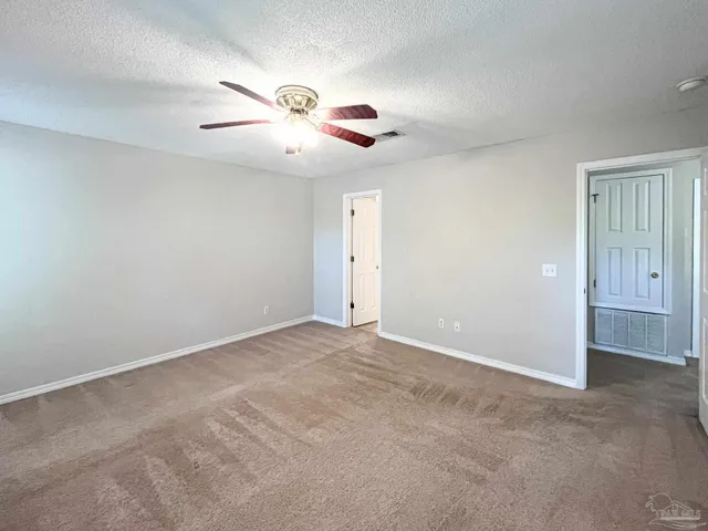 an empty room with windows and fan