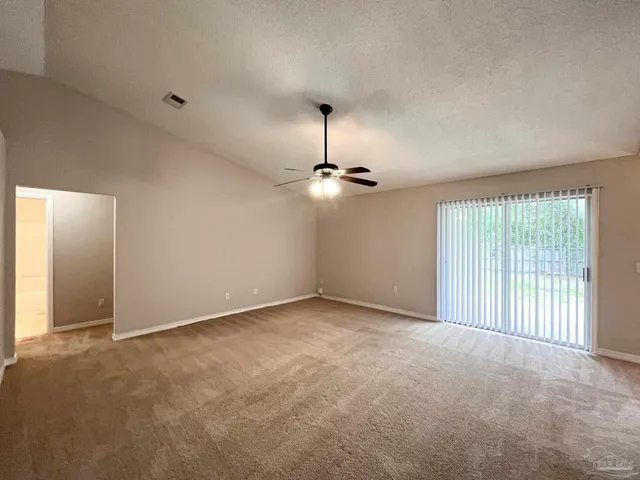 an empty room with chandelier fan and windows