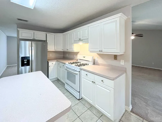 a kitchen with granite countertop white cabinets and white appliances