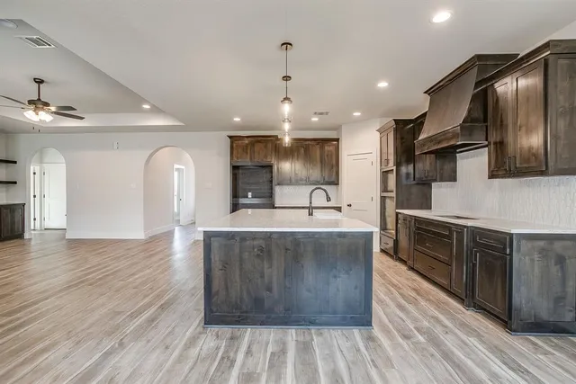 a large kitchen with stainless steel appliances granite countertop a lot of counter space and wooden floors
