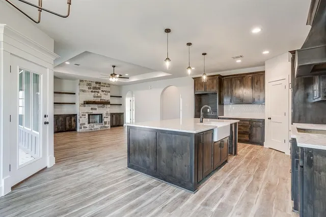 a large kitchen with stainless steel appliances kitchen island a large counter top and wooden floors