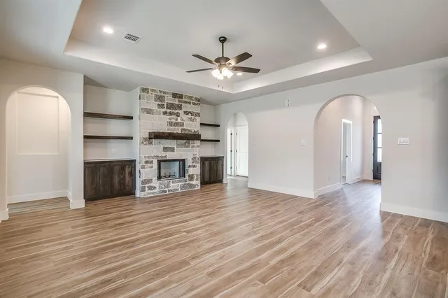 an empty room with wooden floor a fireplace and a window