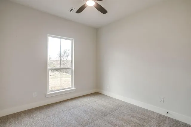 an empty room with a window and a ceiling fan