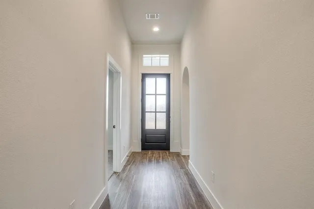 a view of a hallway with wooden floor and a window
