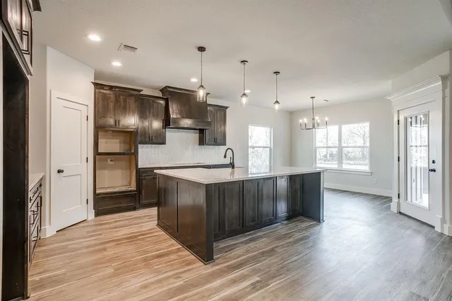 a kitchen with stainless steel appliances granite countertop a refrigerator a sink dishwasher a stove and a large oven with wooden floor