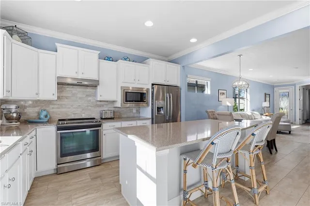 a kitchen with stainless steel appliances granite countertop a stove a sink a microwave a refrigerator and white cabinets