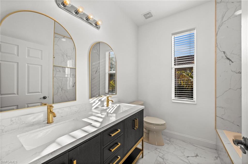 3972 Ruxton Road Naples, FL 34116 - Photo 29 of 41 a bathroom with a granite countertop sink mirror vanity and toilet