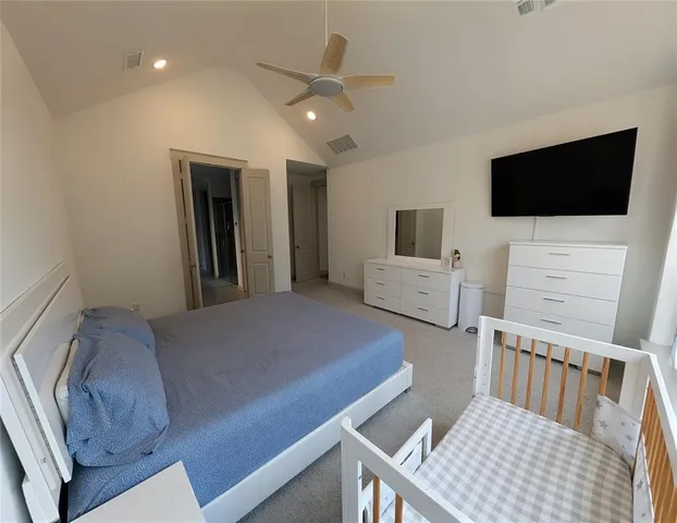 a bedroom with a large bed a flat tv screen and a dresser