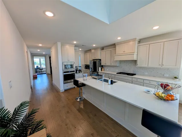 a large white kitchen with lots of counter space a sink and appliances