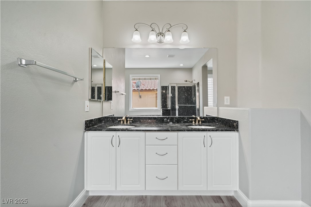 312 Pocono Ranch Avenue North Las Vegas, NV 89031 - Photo 22 of 34 Full bath with a stall shower, a sink, wood finished floors, and baseboards