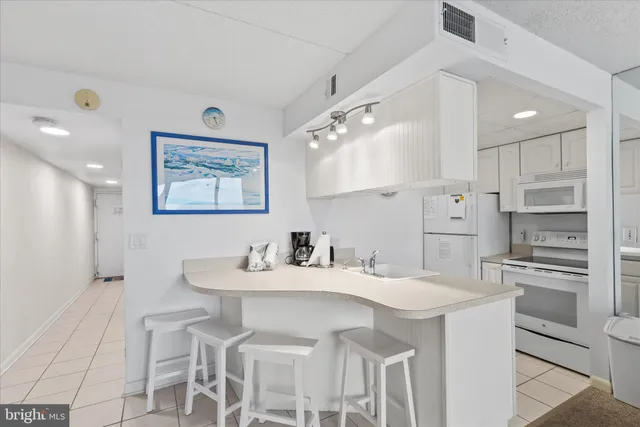 a view of kitchen with refrigerator and white cabinets