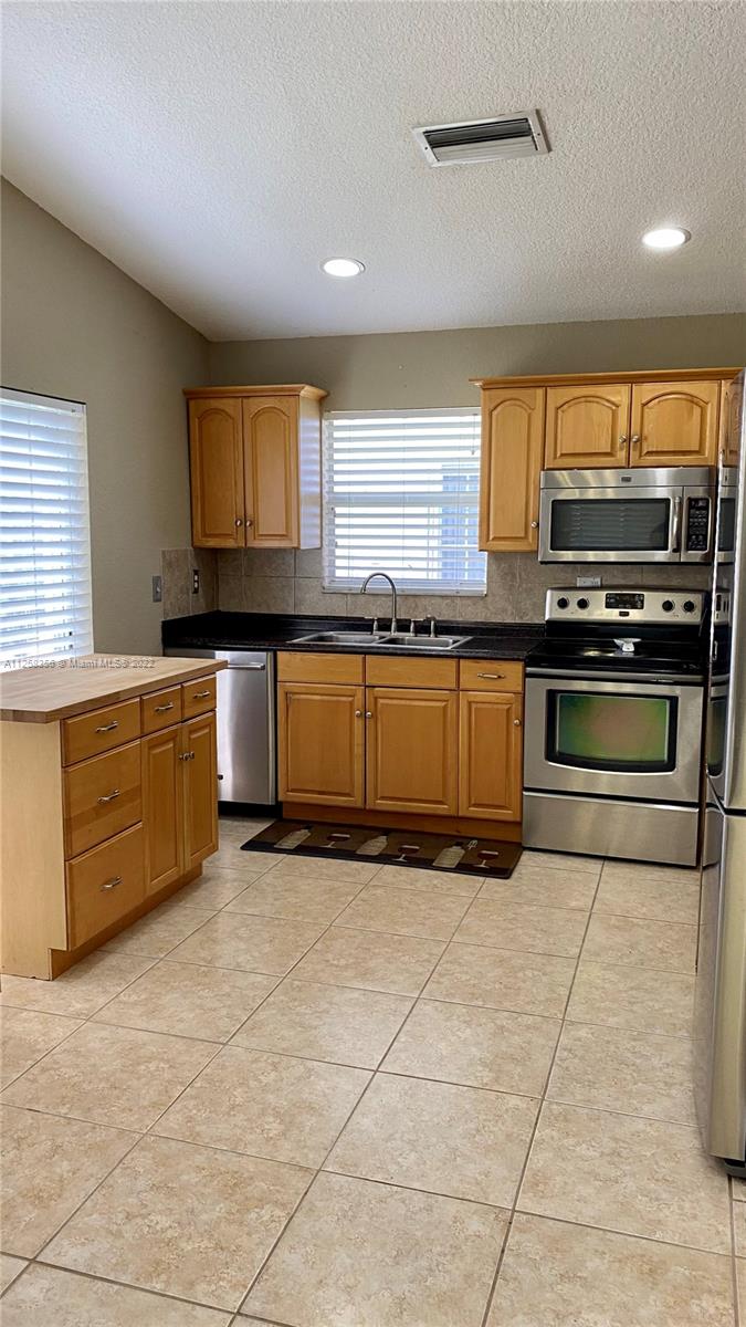 20309 Southwest 86th Court Cutler Bay, FL 33189 - Photo 11 of 59 a kitchen with stainless steel appliances granite countertop a stove sink and cabinets