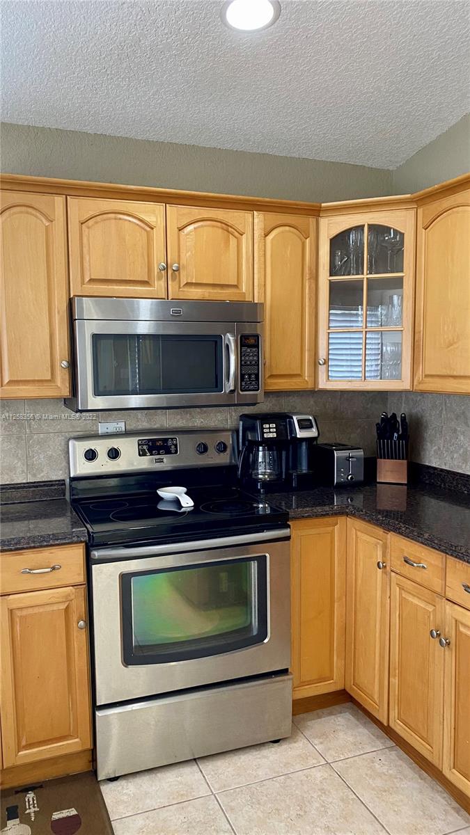 20309 Southwest 86th Court Cutler Bay, FL 33189 - Photo 14 of 59 a kitchen with granite countertop a stove top oven cabinetry a sink and a microwave
